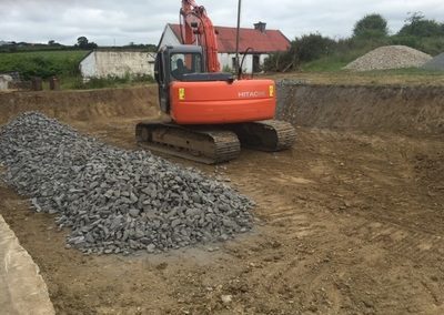 Excavator - digging foundation and filling with stone